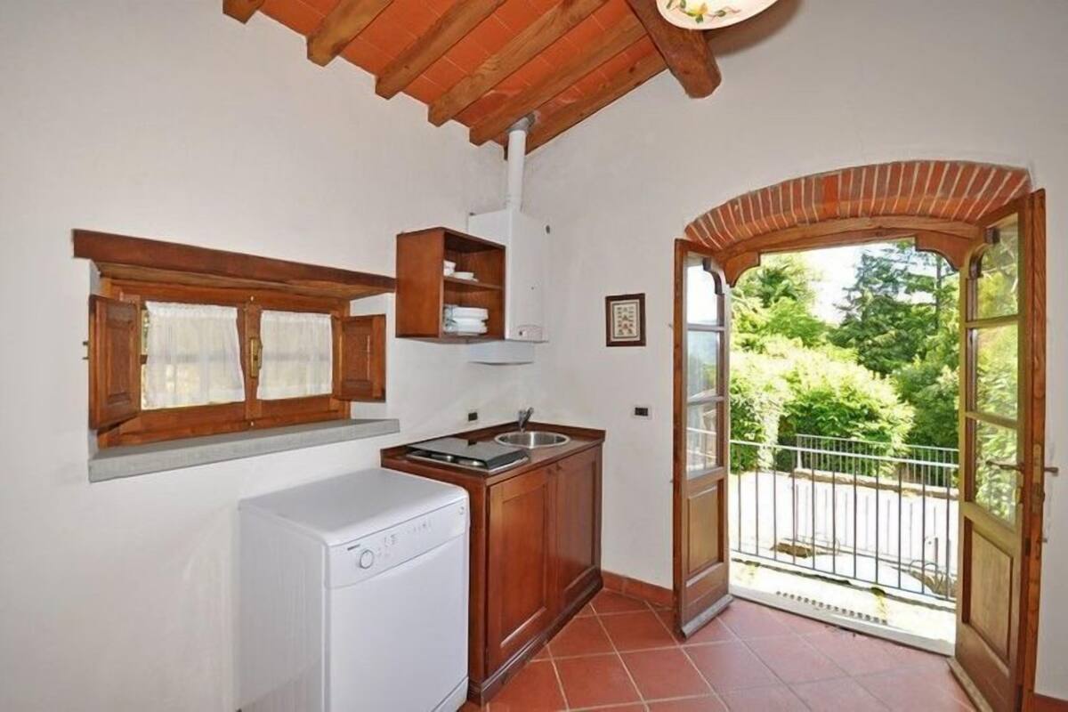 A compact kitchen with a built-in washer, a small sink, and a window with curtains.
