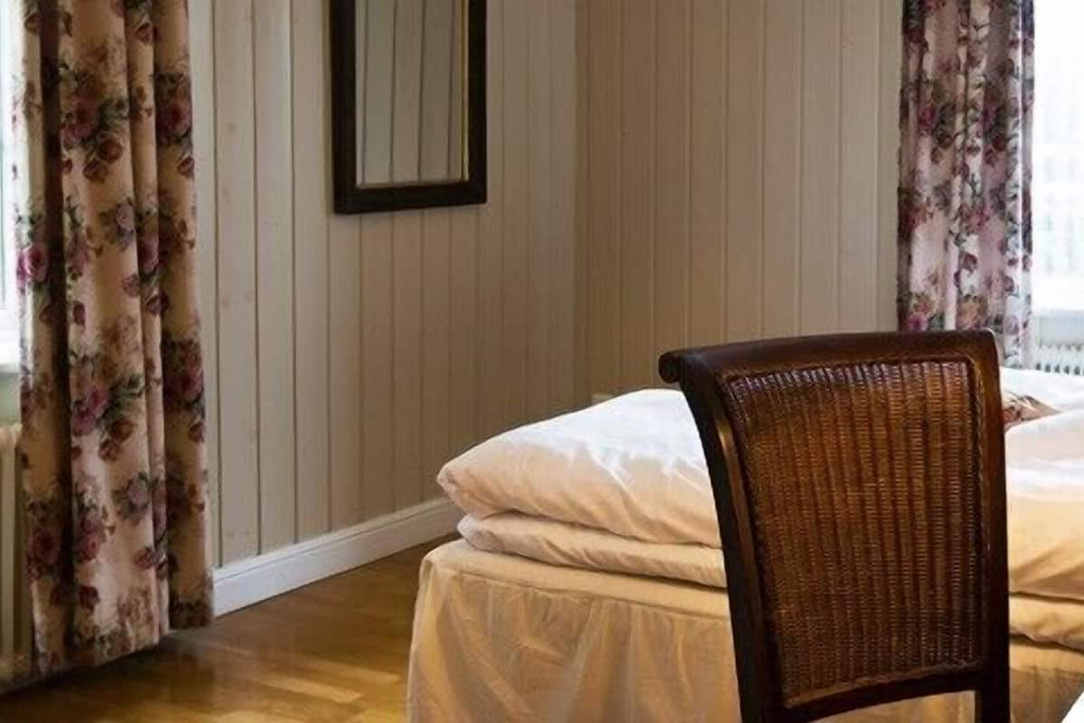 Una habitación de hotel con una cama, una silla, un escritorio y una lámpara.
