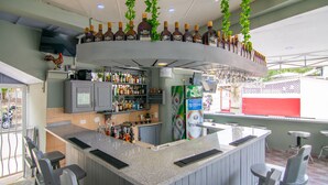 A bar area with a curved counter, seating, and a television mounted on the wall. - Hotel Plaza Europa (Sosúa)