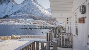 Una propiedad frente al agua cubierta de nieve, con una terraza de madera y montañas al fondo, y un letrero que indica la habitación número 4.