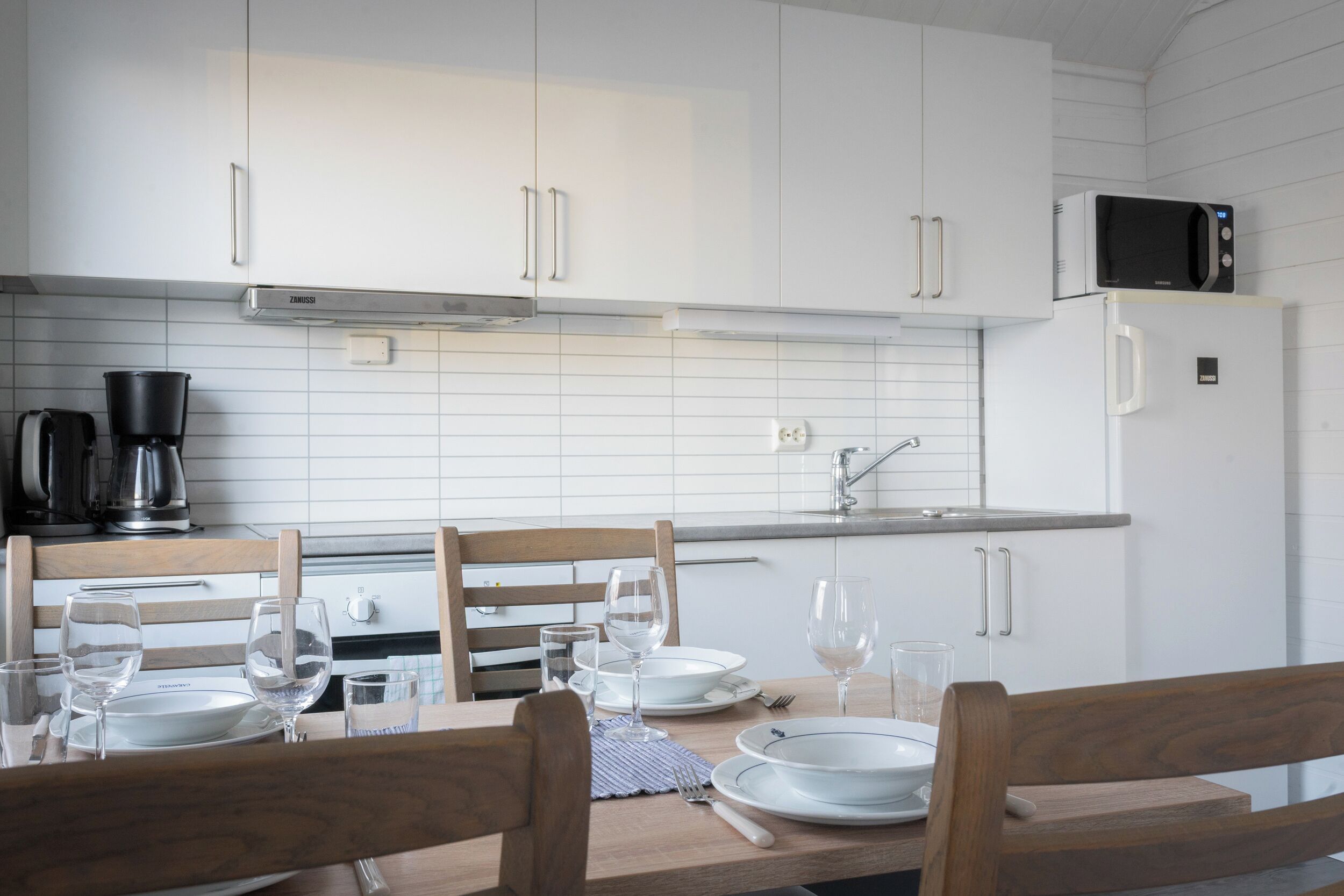 Una cocina moderna con armarios blancos, un microondas y una cafetera.