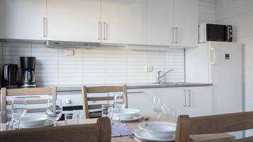 Una cocina moderna con armarios blancos, un microondas y una cafetera.