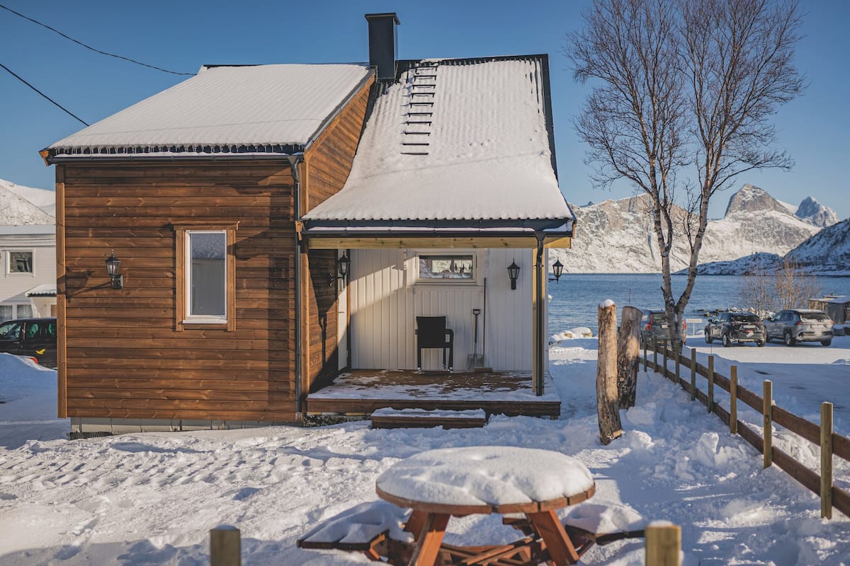 Une cabane en bois avec un toit enneigé et une véranda.