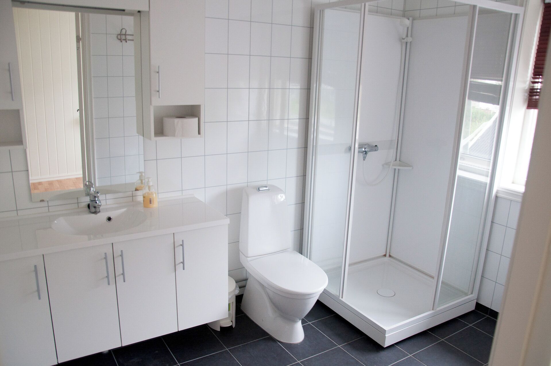 A modern bathroom with a white sink, toilet, and glass-enclosed shower.