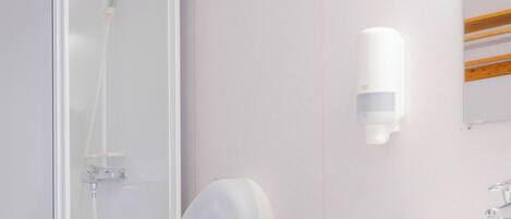 A bathroom with a glass shower enclosure, a white toilet, and a white sink with a mirror above it.