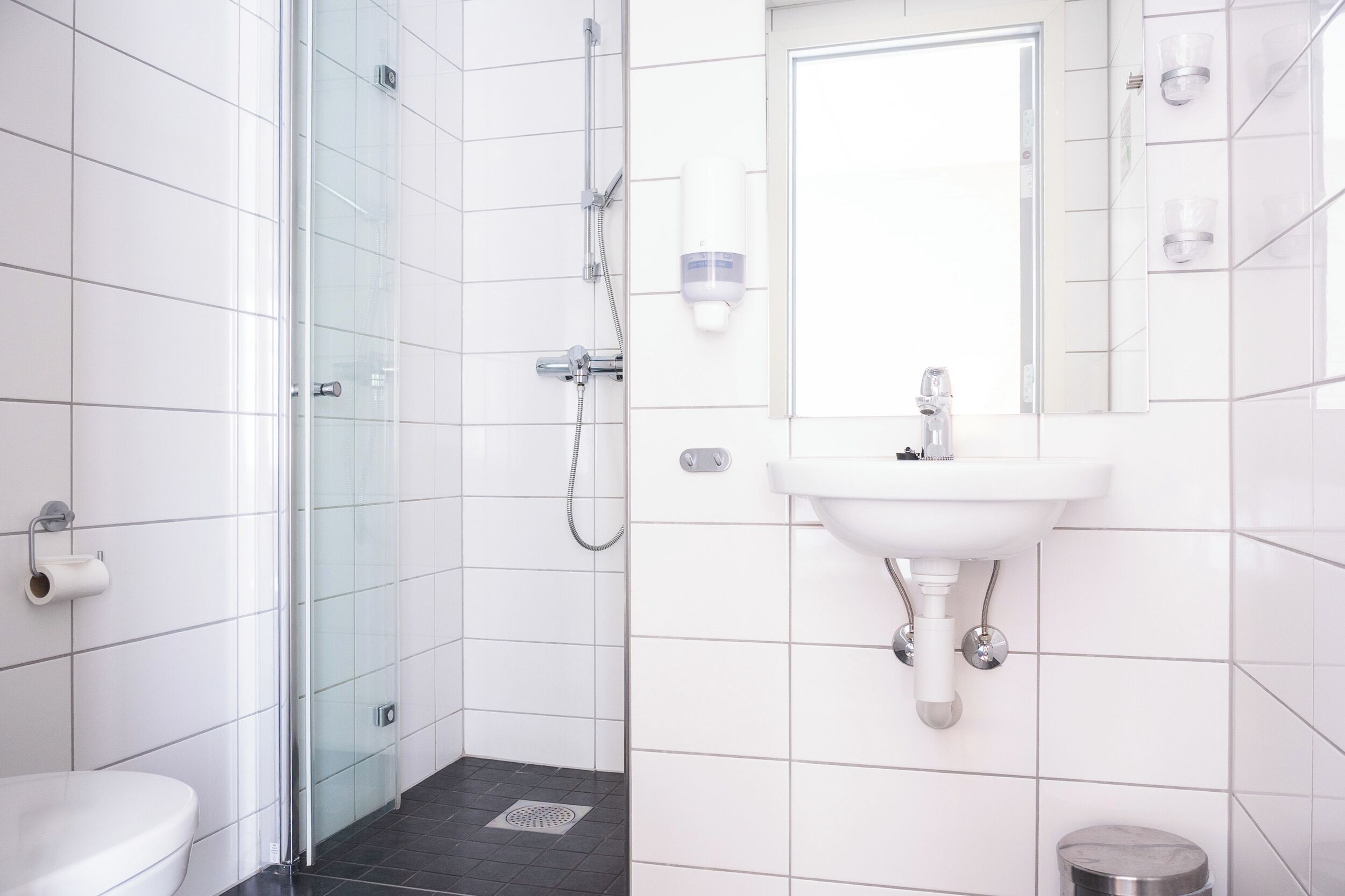 A modern bathroom with a glass shower enclosure, a white sink, and a toilet.