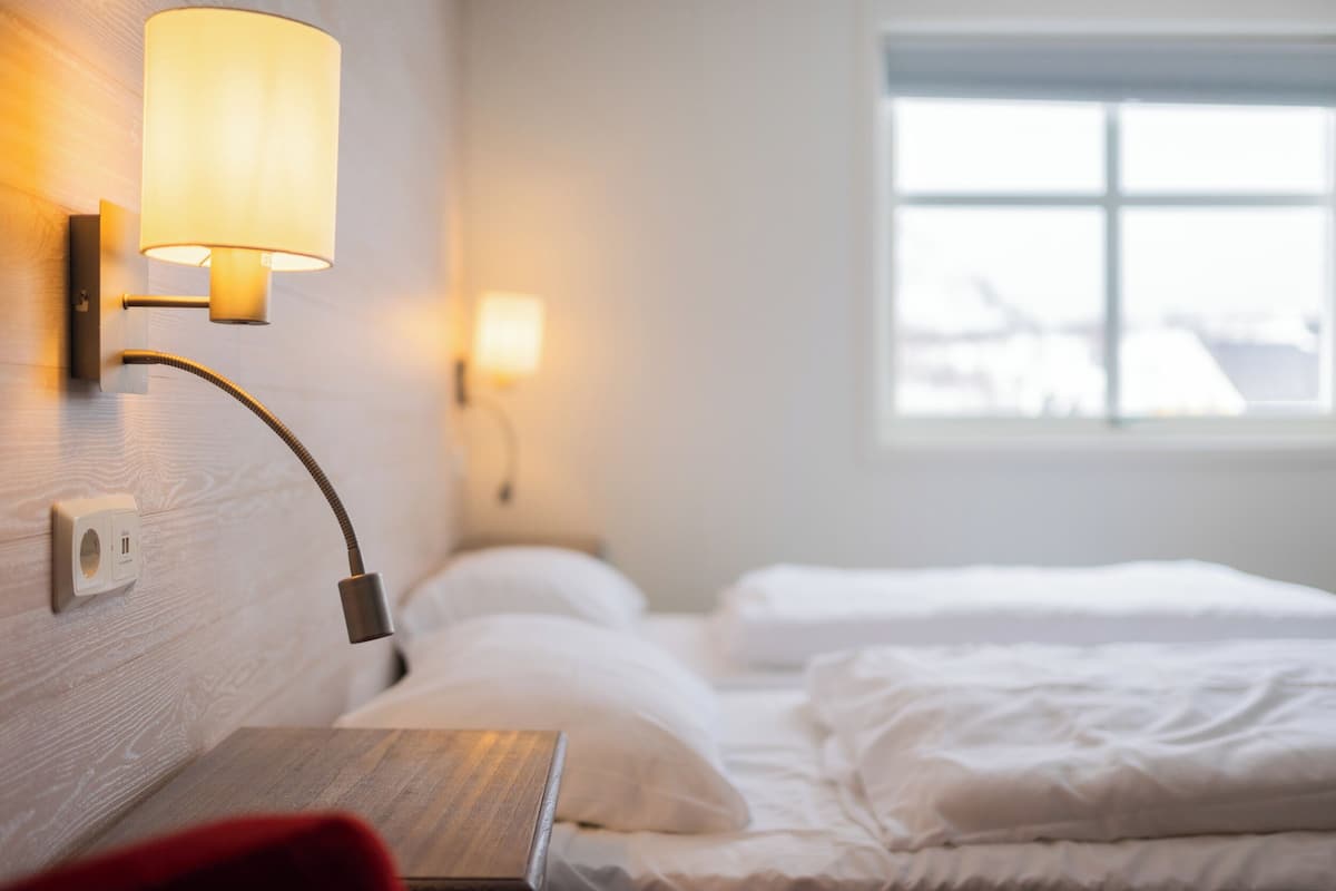Une chambre d’hôtel avec un lit, une table de chevet, une lampe et une fenêtre.