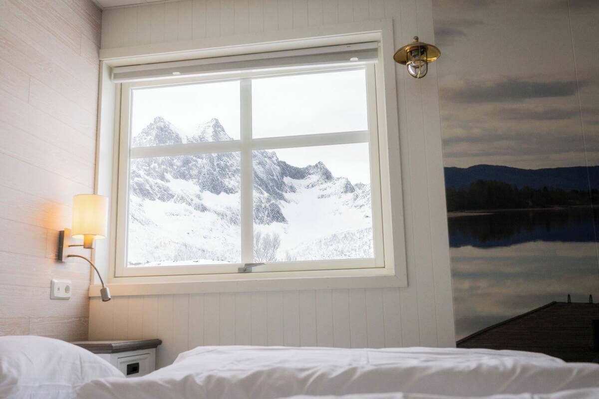 Une chambre avec une grande fenêtre donnant sur un paysage montagneux enneigé.