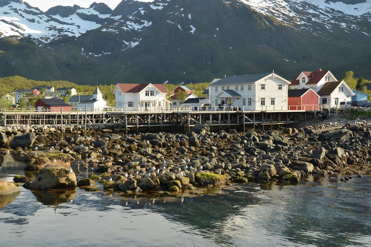 Une ville côtière avec des maisons construites sur pilotis au-dessus de l’eau, entourée de montagnes et de côtes rocheuses.