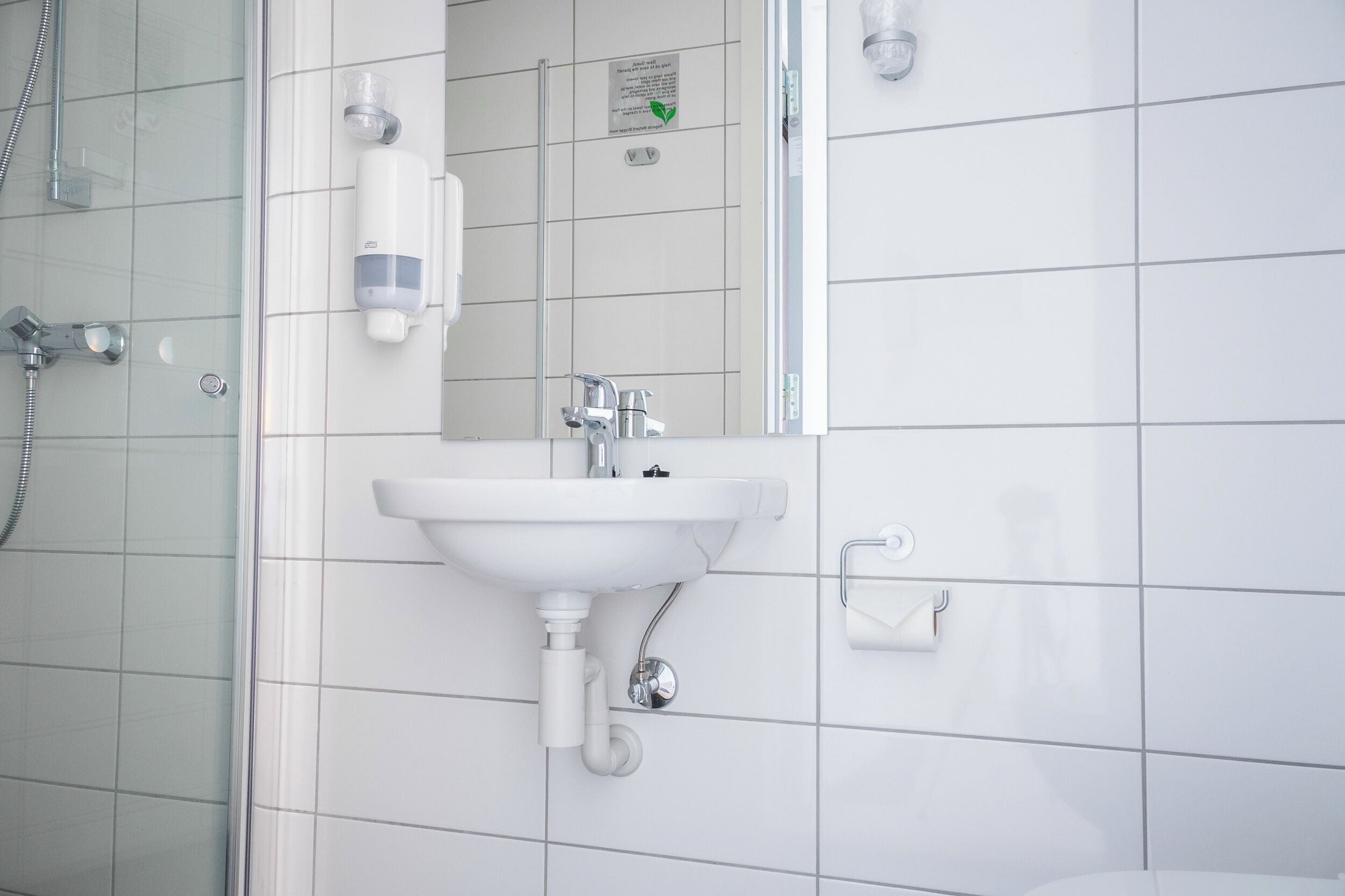 A modern bathroom with a white sink, a glass shower enclosure, and a mirror.