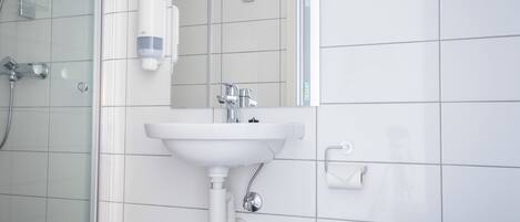 A modern bathroom with a white sink, a glass shower enclosure, and a mirror.