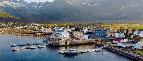 En kuststad med en hamn, båtar och ett bergigt landskap i bakgrunden.