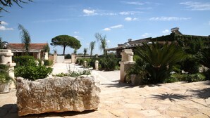 A courtyard with stone flooring, a large rock, and a tree.