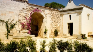A stone building with an arched entrance, a small door, and steps leading up to it.