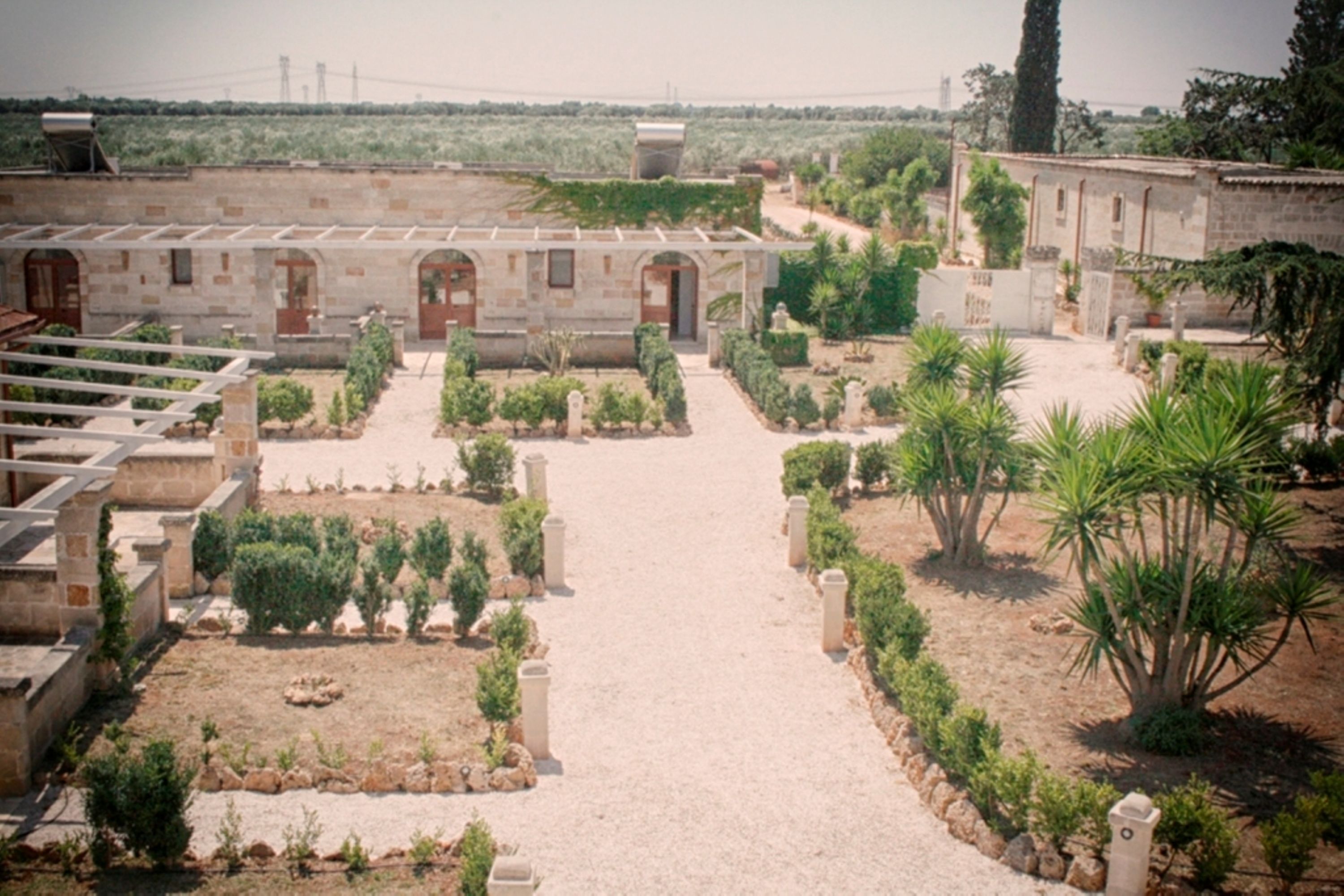 A courtyard with a central pathway, surrounded by stone buildings and greenery.