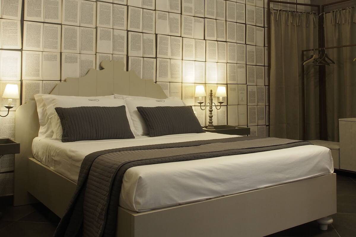A modern bedroom with a large bed, a wall-mounted air conditioner, and a chandelier.