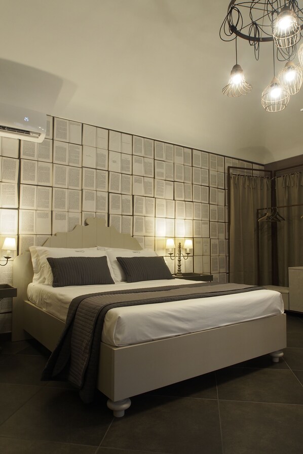 A modern bedroom with a large bed, a wall-mounted air conditioner, and a chandelier. - Terrazzani Suite (Comiso)