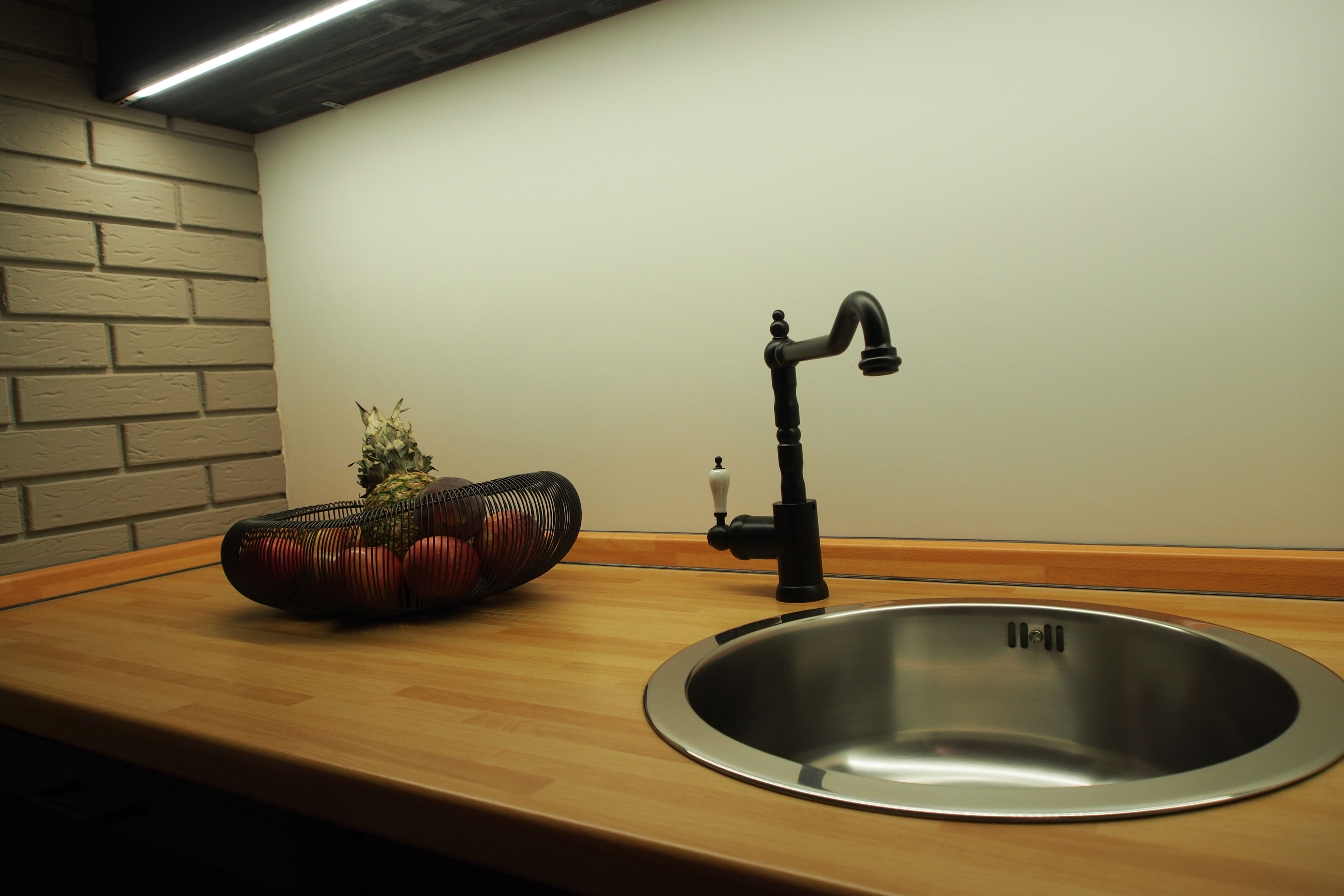 Una cocina con un lavamanos de acero inoxidable, un grifo negro y una encimera de madera.