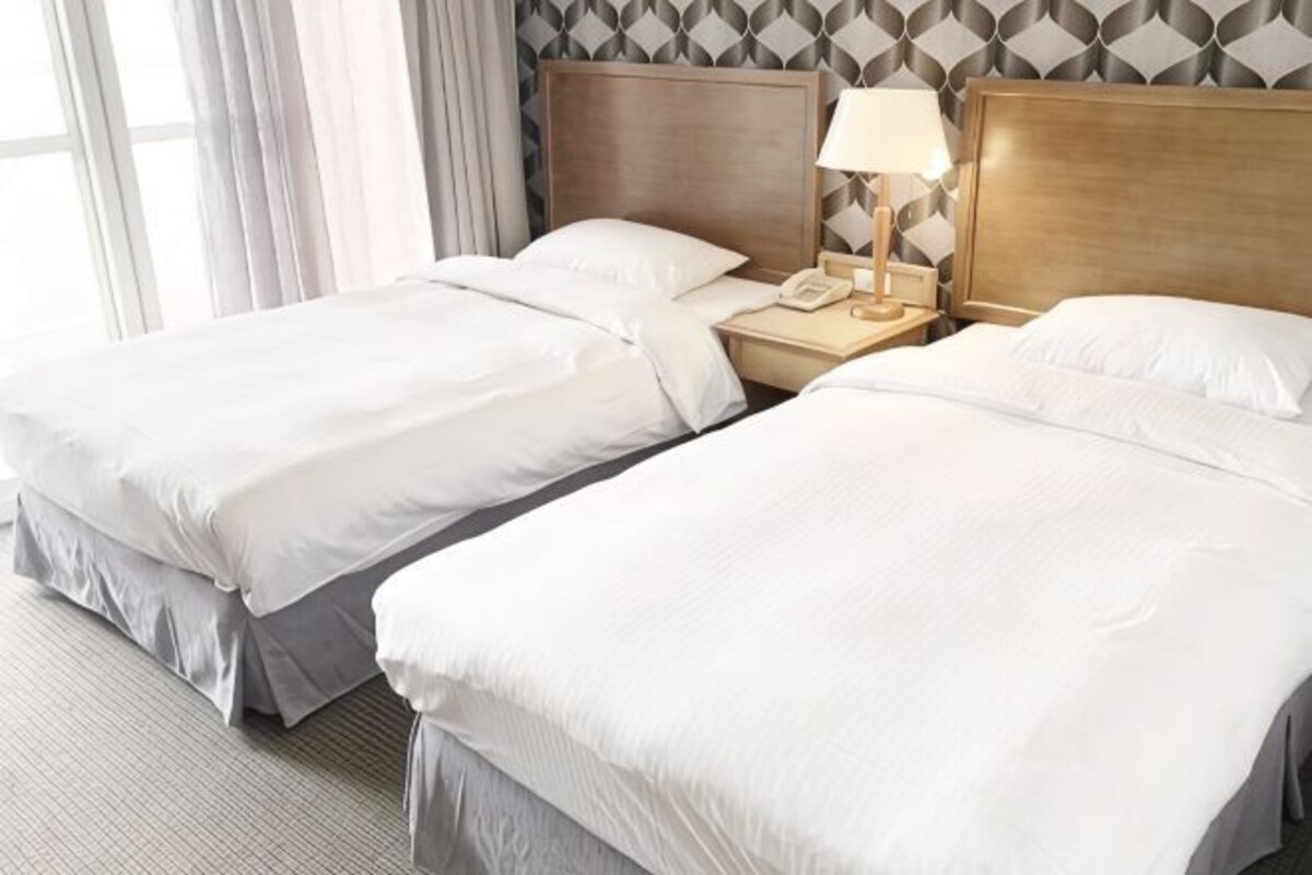 Twee eenpersoonsbedden met houten hoofdborden, een nachtkastje met een lamp en een telefoon.