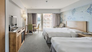 A hotel room with two beds, a desk with a TV, a chair, and a view of the outside.