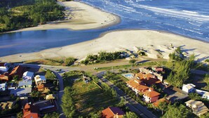 Vue aérienne d’une zone côtière avec une plage, une petite île et des immeubles résidentiels.