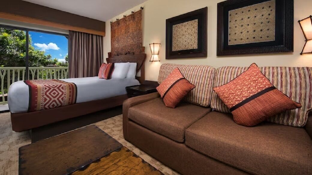 Une chambre d’hôtel avec un lit, un canapé, une table de chevet, une lampe et une vue sur l’extérieur.
