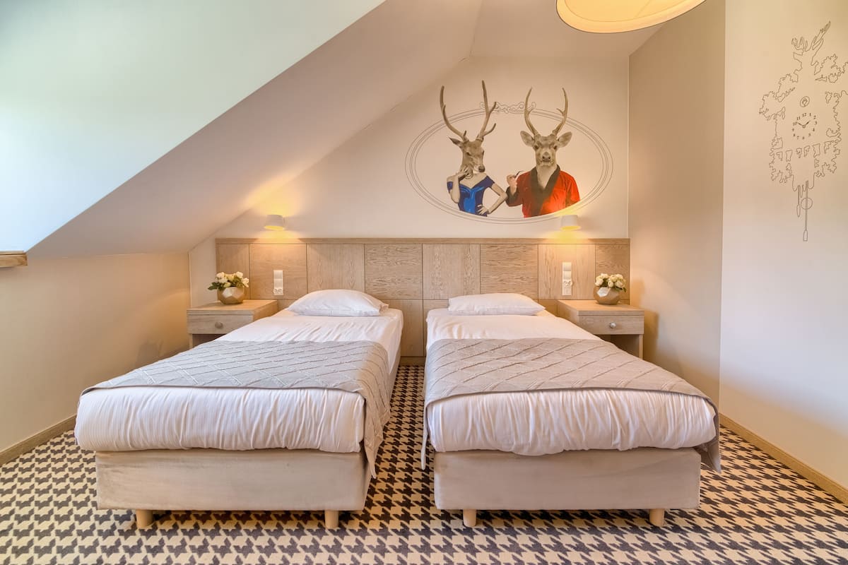 Une chambre avec deux lits, un sol à motifs et une fresque murale représentant des têtes de cerfs.
