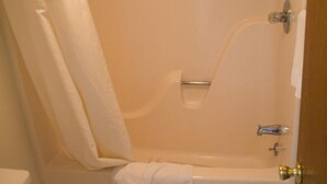 A bathroom with a bathtub, a shower curtain, and a toilet. - Tazewell Motor Lodge (Tazewell)