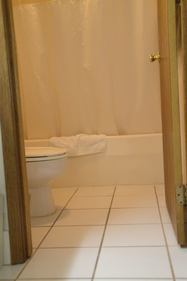 Un baño con inodoro, bañera y cortina de ducha.
