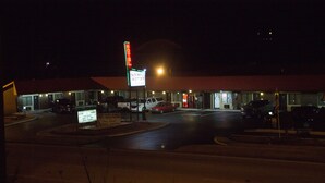 A motel with a red roof, a parking lot, and a signboard. - Tazewell Motor Lodge (Tazewell)