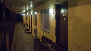 A corridor with benches, doors, and an exit sign. - Tazewell Motor Lodge (Tazewell)