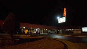 A motel with a large sign, a parking lot, and a few vehicles. - Tazewell Motor Lodge (Tazewell)