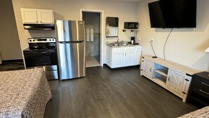 A modern kitchen with stainless steel appliances, a flat-screen TV mounted above the counter, and a separate dining area with a wooden table and chairs. - Pine View Inn (Virginia)