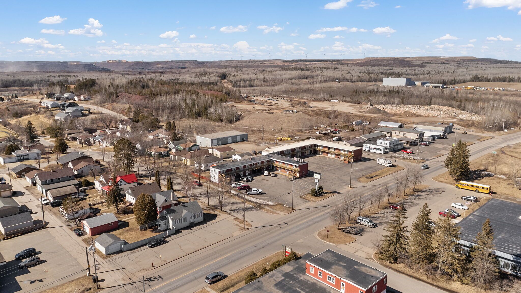 An aerial view of a small town with residential houses, a central building complex, and a road.