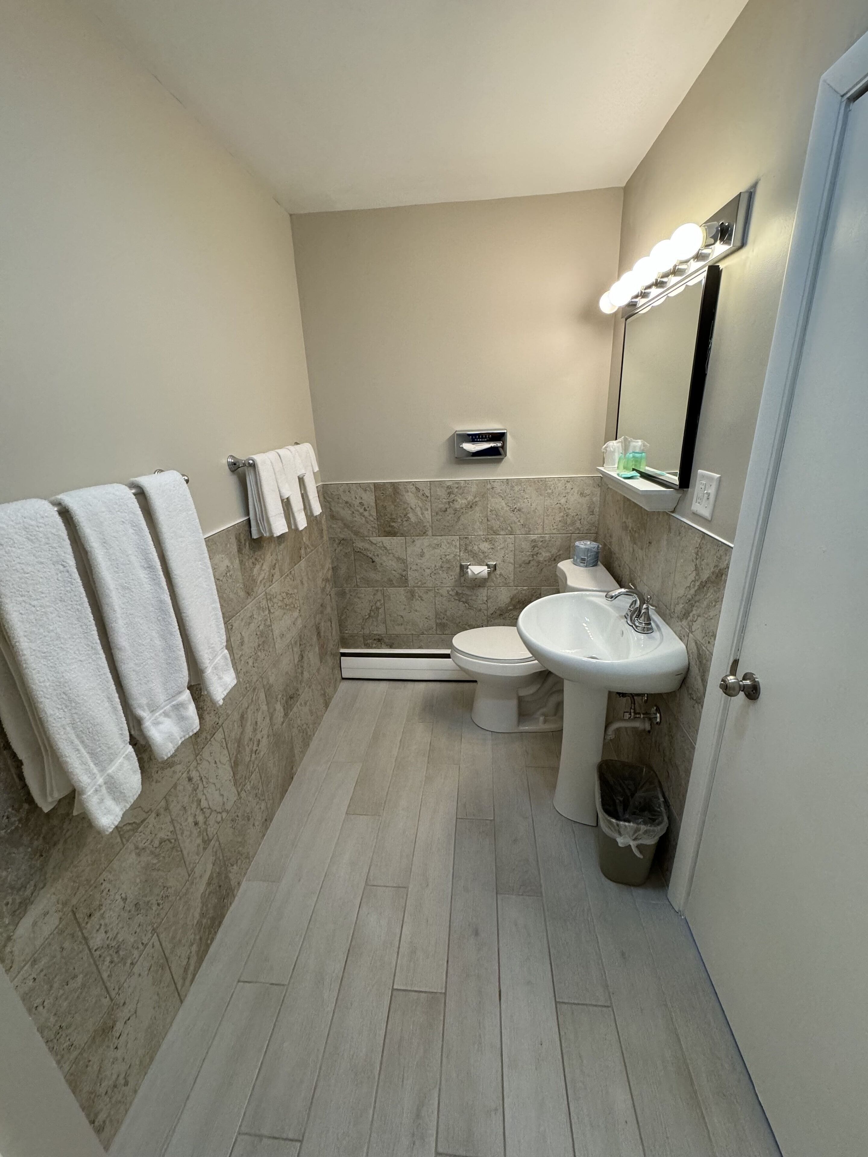 A compact bathroom with a toilet, sink, and towel rack.