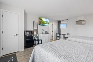 A hotel room with a bed, a desk, a chair, a TV, a wardrobe, and a window.