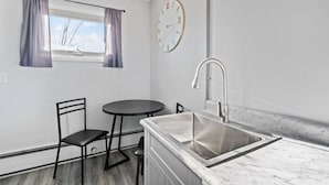 A compact kitchen with a sink, a round table, and two chairs. - Pine View Inn (Virginia)