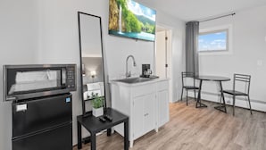 A compact kitchenette with a microwave, sink, and a small dining area with chairs. - Pine View Inn (Virginia)