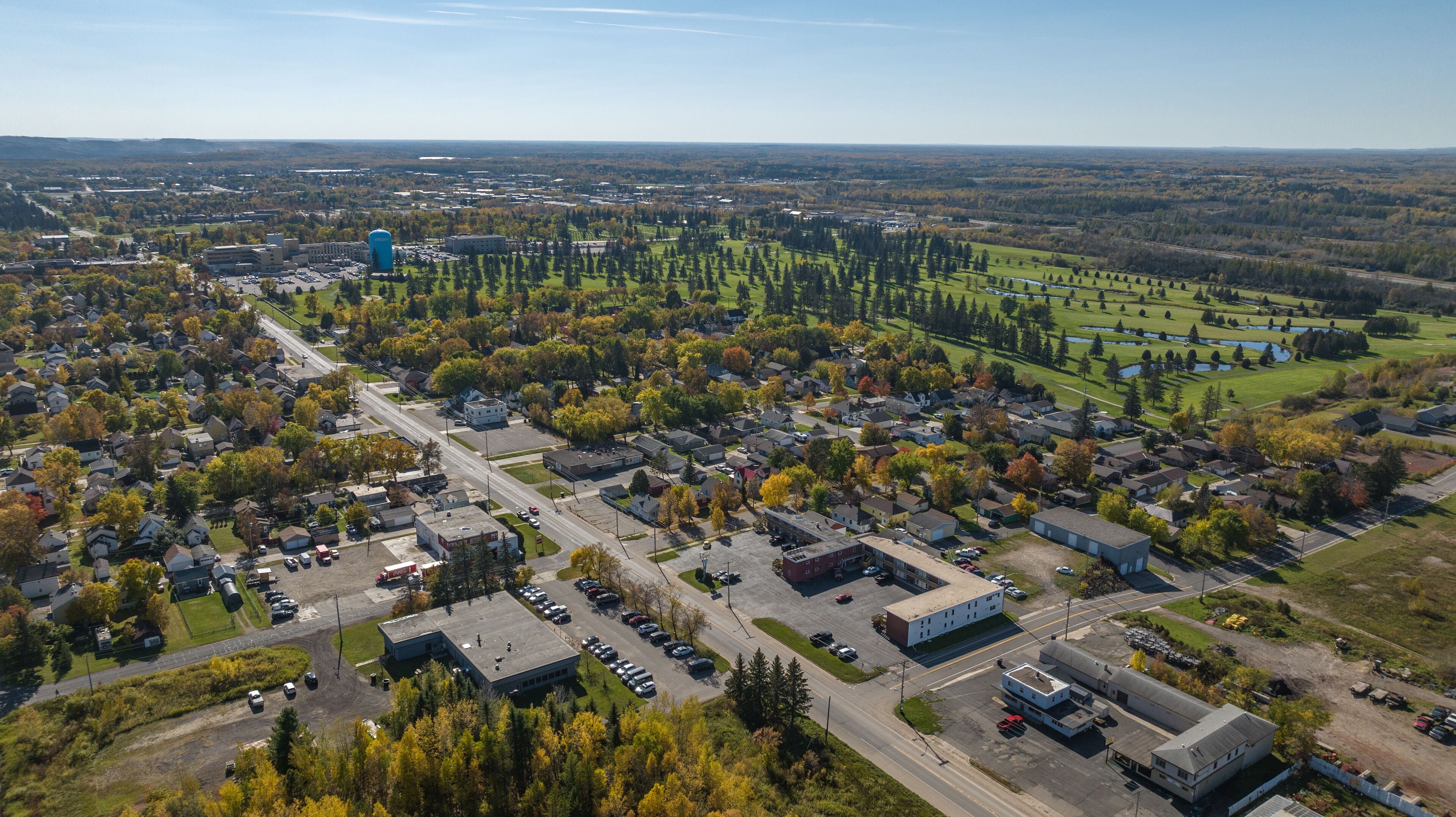 Ett flygbildsbild av ett förortsområde med bostadshus, en stor industribyggnad och en golfbana.