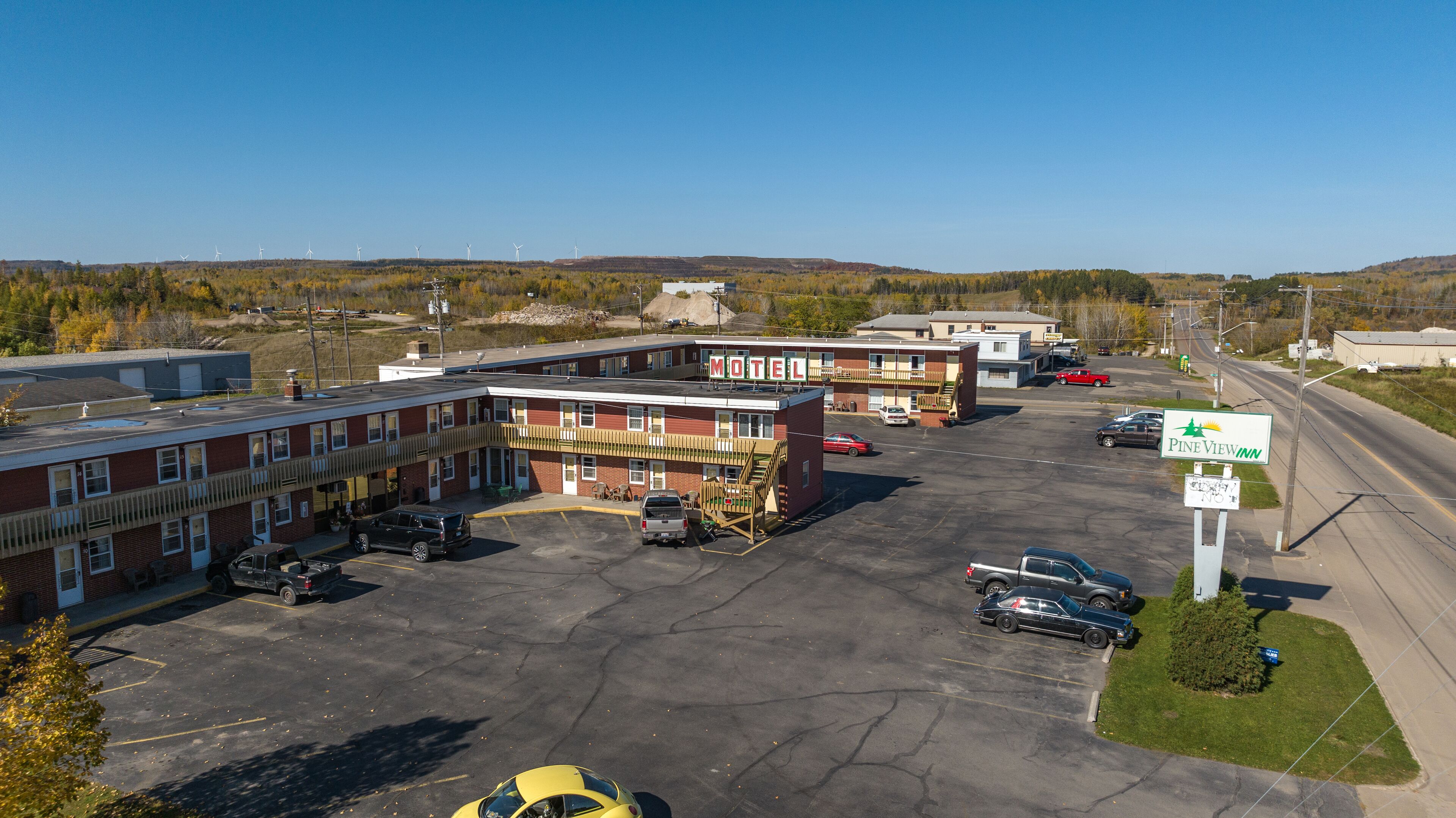 A motel with a parking lot, a building with a 'Motel' sign, and a Pine View Inn sign.