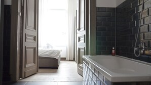 A hotel room with a large bathtub, a bed, and a view of the outdoors. - Amazing Apartment Antwerp South (Antwerp)
