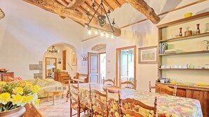 A dining area with a long table, wooden chairs, and a floral tablecloth. There are shelves with dishes and a chandelier above the table. - Montescalari (Figline e Incisa Valdarno)
