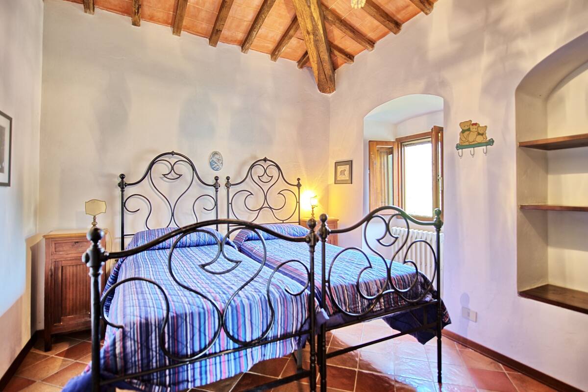 A bedroom with a metal bed frame, a wooden cabinet, and a window with a view.