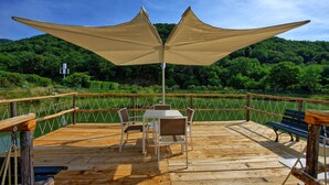 A wooden deck with a table and chairs, a bench, and a large canopy. - Montescalari (Figline e Incisa Valdarno)
