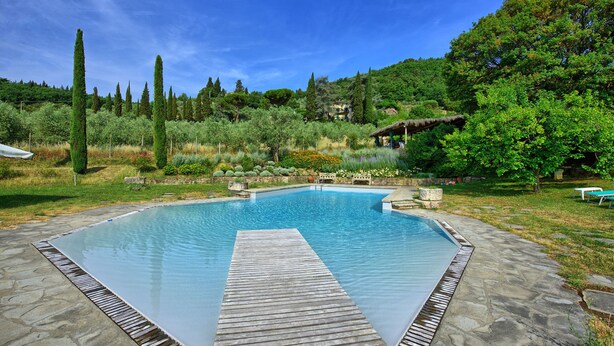 A rectangular pool with a wooden deck in the center, surrounded by stone tiles. - Montescalari (Figline e Incisa Valdarno)