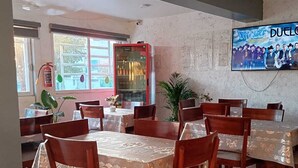 A restaurant with wooden tables and chairs, a tiled floor, a fire extinguisher, and a refrigerator. - Hotel Esperanza (Mazatlán)