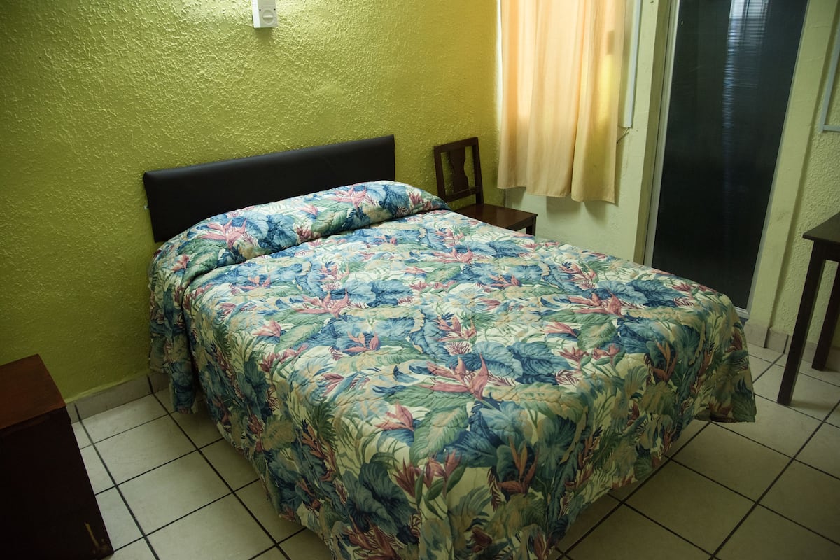 Una habitación con una cama, una silla y una puerta.