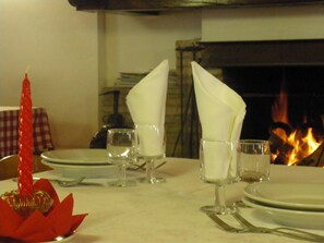 A dining table set with plates, glasses, and napkins. A red candle is placed on the table. - Agriturismo Orsaiola (Urbania)