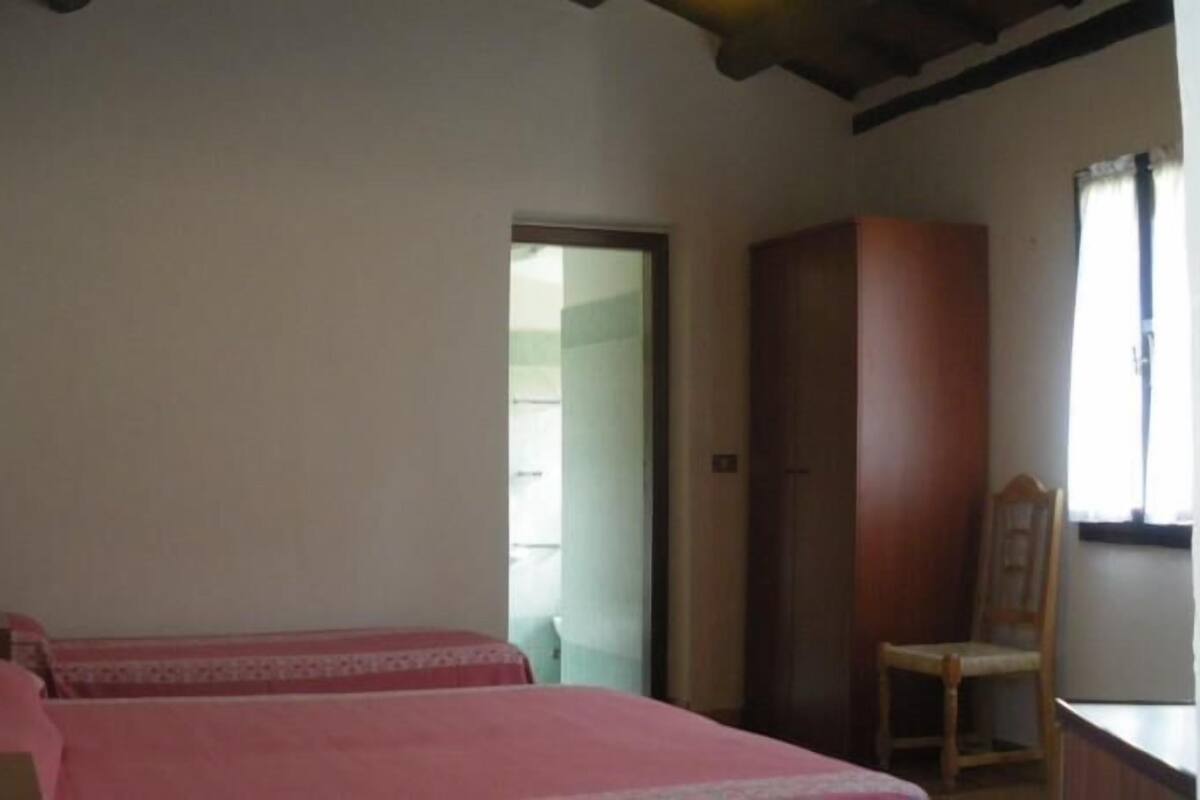 A room with two beds, a wooden wardrobe, and a chair.
