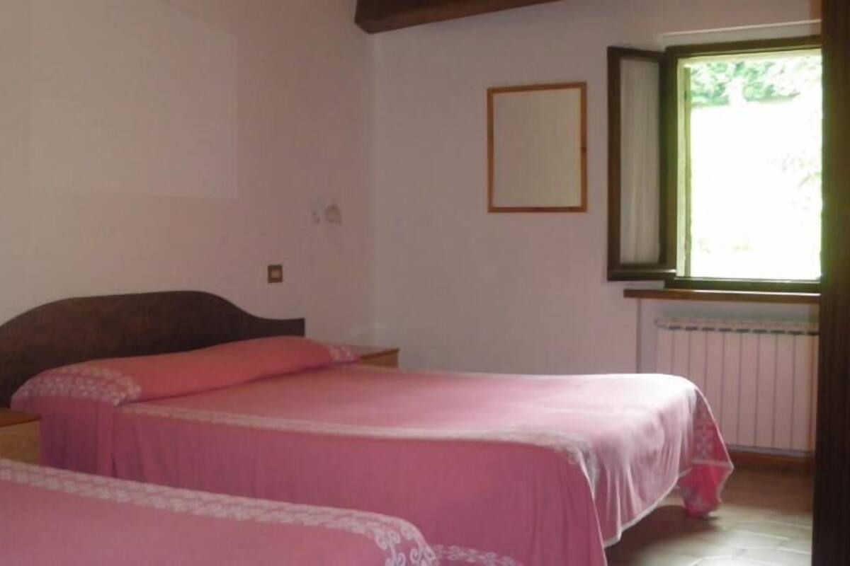 A bedroom with two beds, a window, and a radiator.